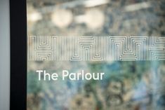 the parlour logo is displayed on a glass door with an artistic pattern behind it