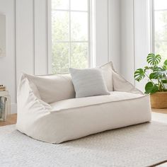 a white couch sitting on top of a rug in a living room next to two windows