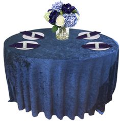 a blue table cloth with white and purple flowers on the top is set up for an event