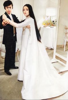 a young man and woman dressed up in formal wear standing next to each other holding hands