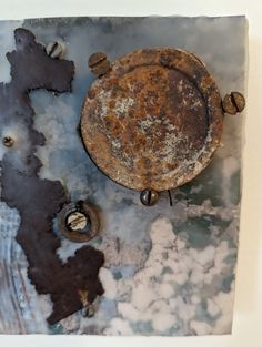 an old rusted metal plate sitting on top of a white wall next to some screws