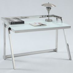 a glass desk with metal legs and a lamp on top, in front of a white background