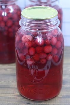 a jar filled with cranberries sitting on top of a wooden table next to other jars