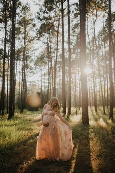 a woman in a dress walking through the woods with her back turned to the camera