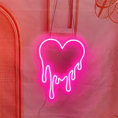 a neon pink heart shaped sign hanging from a wall