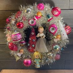 a christmas wreath with barbie dolls and ornaments hanging on the front door ornament