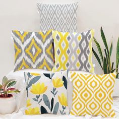 a bed with yellow and gray pillows on top of it next to a potted plant