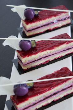 three pieces of cake with purple and white toppings sitting on top of each other