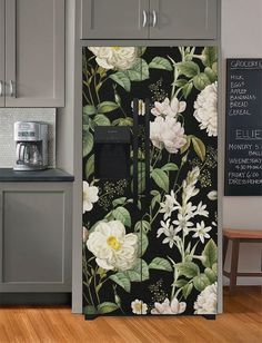 a kitchen with gray cabinets and white flowers on the wall next to a black refrigerator