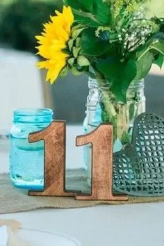 the table is set with mason jars, sunflowers and blue vases on it