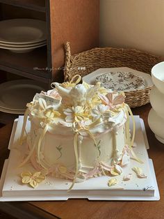 a cake with flowers on it sitting on top of a table next to plates and bowls