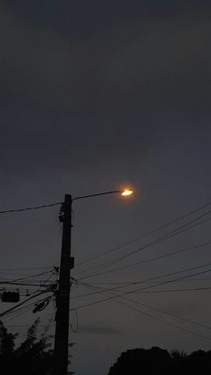 the sun is setting behind power lines and telephone poles on a dark night with no one in sight