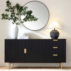 a black and gold sideboard with a round mirror on the wall next to it