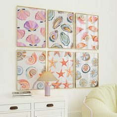 three seashells are hanging on the wall above a white dresser with drawers and a lamp