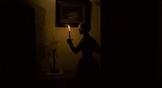 a woman holding a candle in the dark