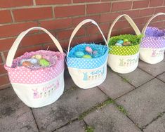 three easter baskets with eggs in them on the sidewalk next to a brick wall and grass