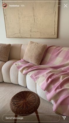 a couch covered in a pink and white striped blanket next to a painting on the wall