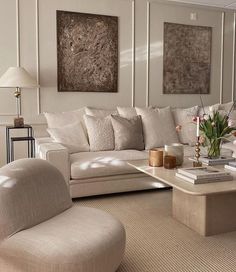 a living room filled with white furniture and flowers in vases on the coffee table