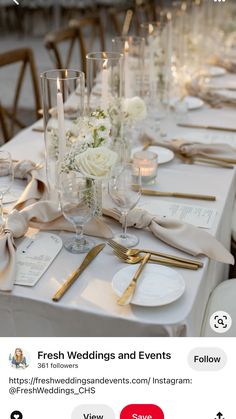 the table is set with white flowers, candles and napkins for an elegant wedding