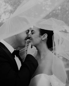 black and white photograph of bride and groom kissing each other under the veil on their wedding day