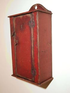 an old red cabinet hanging on the wall