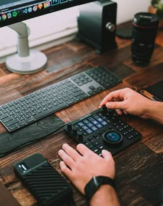 a man is typing on a keyboard at his desk with two computer monitors behind him