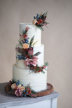 a three tiered wedding cake with flowers on top