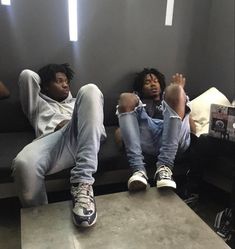 two young men sitting on a couch with their feet propped up against each other's legs