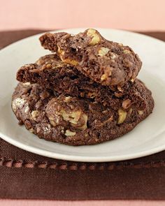 three cookies stacked on top of each other in a white plate next to a glass of milk