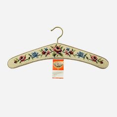 a white hanger with flowers on it and a tag hanging from the top of it