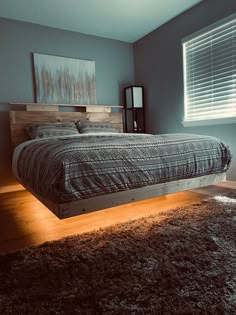 a bed sitting on top of a wooden floor in a bedroom next to a window