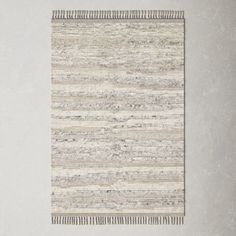 an area rug with stripes and fringes on the floor in front of a white wall