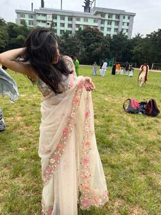 a woman is standing in the grass with her hand on her hip, holding onto an unbuttoned sari