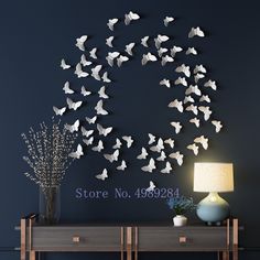 there is a clock made out of white paper butterflies on the wall next to a table