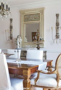 an elegant dining room with chandelier and white chairs