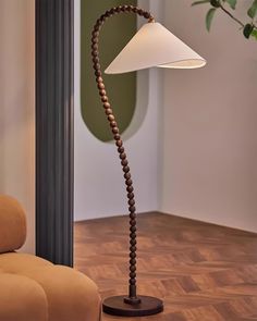 a lamp that is on top of a wooden floor next to a chair and potted plant