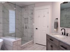 a bathroom with marble counter tops and white tile walls, along with a walk in shower