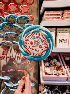 a person is holding a lollipop in front of some candies and candy