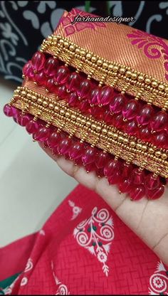 a hand holding some red and gold bracelets