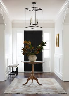 a room with a table, chairs and a chandelier hanging from the ceiling