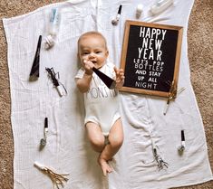 a baby laying on top of a blanket next to a sign that says happy new year