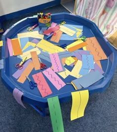 a blue table topped with lots of cut out pieces of paper and scissors on top of it