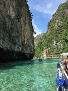 the boat is traveling through the clear water near some mountains and cliffs in the ocean