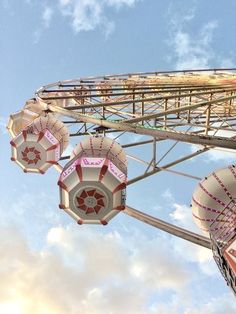 the ferris wheel has pink and white decorations hanging from it's sides in front of a cloudy blue sky