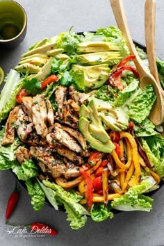 a salad with chicken, peppers and avocado on it