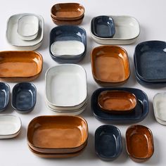 many different colored plates and bowls on a white surface