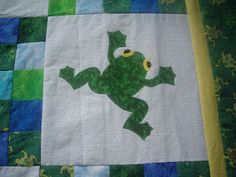 a green frog on a blue and white quilt