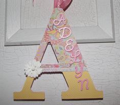 the letter a is made out of paper and has a pink bow hanging from it