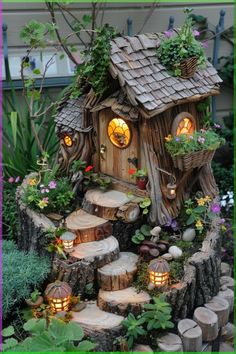 a fairy house made out of tree stumps with lights in the windows and steps leading up to it