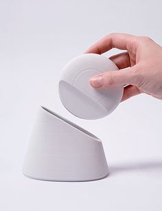 a hand is holding a white object in front of it's base on a white surface